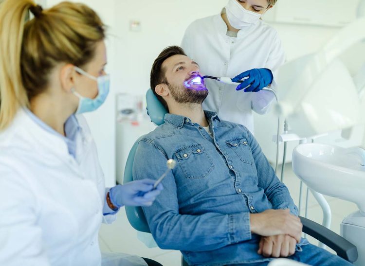 Photo of a male patient visiting dentist for teeth whitening in clinic.