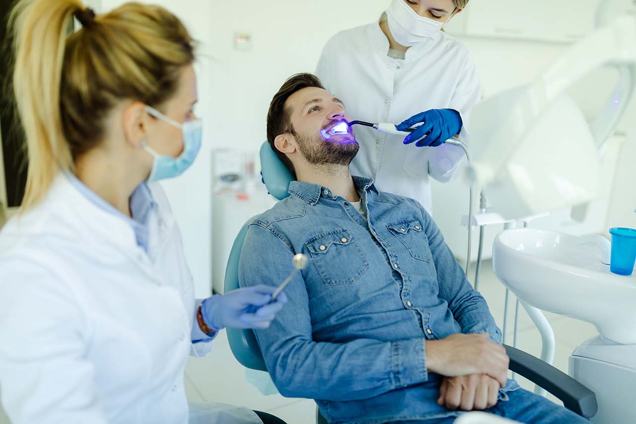Photo of a male patient visiting dentist for teeth whitening in clinic.